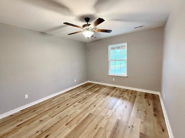 unfurnished room with a ceiling fan, baseboards, visible vents, and wood finished floors