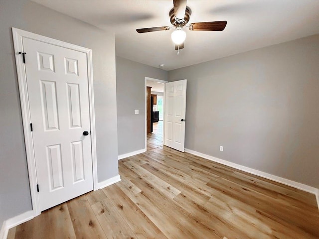 unfurnished bedroom featuring light wood-type flooring, baseboards, and ceiling fan