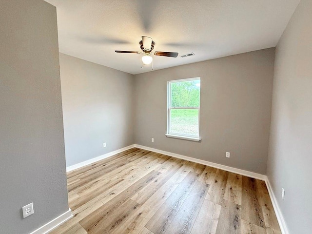empty room featuring baseboards, a ceiling fan, visible vents, and hardwood / wood-style flooring