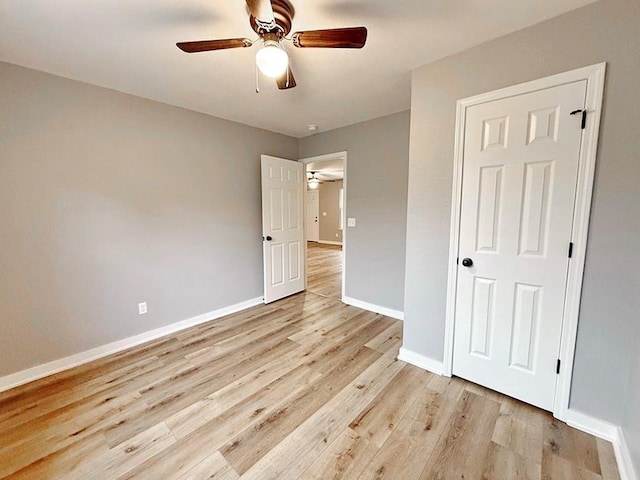 unfurnished bedroom featuring baseboards, ceiling fan, and light wood-style flooring