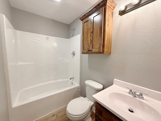bathroom with a textured wall, vanity, toilet, shower / bath combination, and wood finished floors
