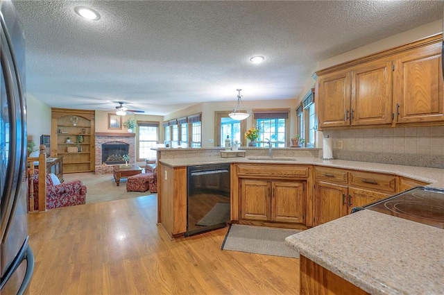 14241 W 113th Ter, Olathe, KS 66062 - kitchen featuring black appliances, a sink, a peninsula, a textured ceiling, and light wood finished floors