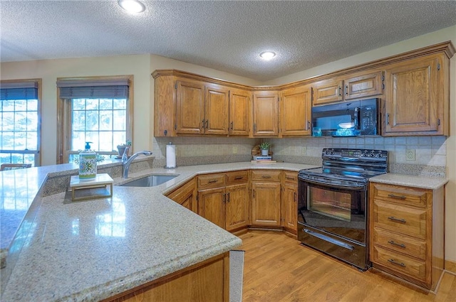 14241 W 113th Ter, Olathe, KS 66062 - kitchen featuring black appliances, a sink, light wood-style floors, a textured ceiling, and brown cabinetry