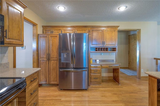 14241 W 113th Ter, Olathe, KS 66062 - kitchen featuring stainless steel fridge with ice dispenser, a textured ceiling, light wood-style floors, brown cabinetry, and light stone counters