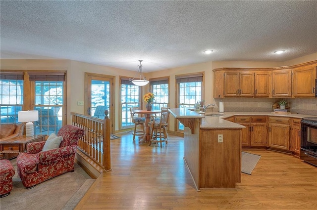 14241 W 113th Ter, Olathe, KS 66062 - kitchen with a peninsula, a textured ceiling, a sink, light wood-style flooring, and black range with electric stovetop