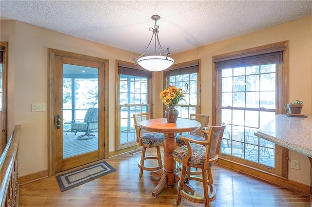 14241 W 113th Ter, Olathe, KS 66062 - dining room featuring wood finished floors, a textured ceiling, and baseboards