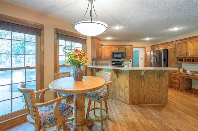 14241 W 113th Ter, Olathe, KS 66062 - kitchen featuring stainless steel fridge, black microwave, range, brown cabinets, and light wood-style floors
