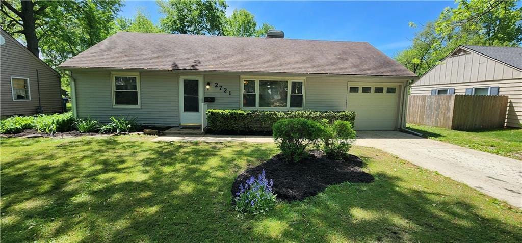 ranch-style house featuring fence, an attached garage, driveway, and a front lawn