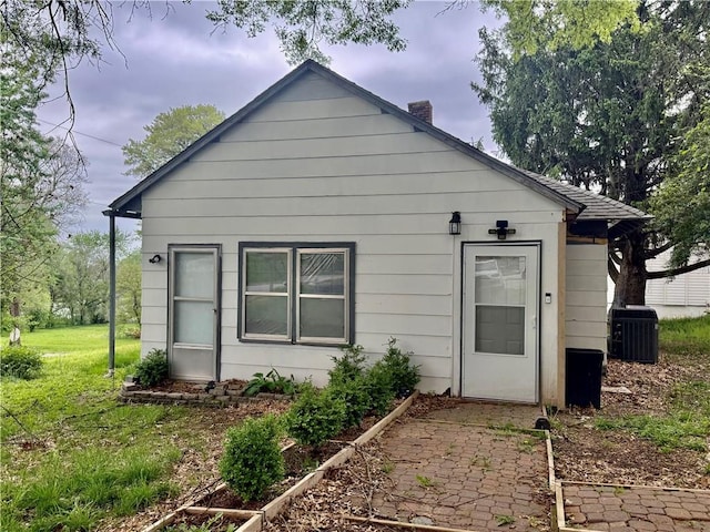 back of property featuring a lawn, central AC, and a chimney