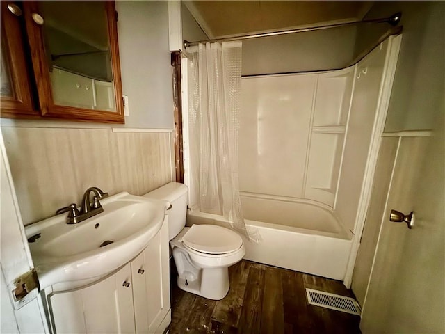 bathroom with wainscoting, toilet, shower / bathtub combination with curtain, wood finished floors, and visible vents
