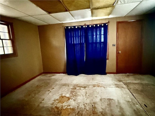 spare room with baseboards and a drop ceiling