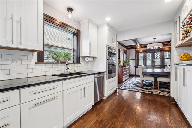 3804 Harrison St, Kansas City, MO 64109 - kitchen featuring a sink, dark wood finished floors, appliances with stainless steel finishes, and dark countertops