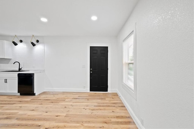 15015 E Truman Rd, Independence, MO 64050 - kitchen featuring a sink, baseboards, white cabinets, black dishwasher, and light wood-style flooring