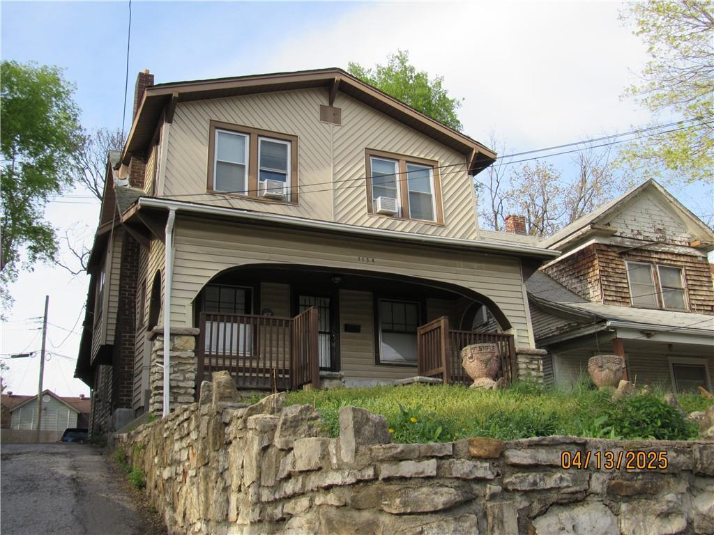 view of front of property featuring a porch, cooling unit, and a chimney