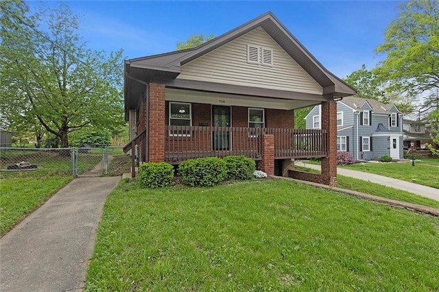708 N River Blvd, Independence, MO 64050 - bungalow-style home with covered porch, a gate, brick siding, fence, and a front lawn