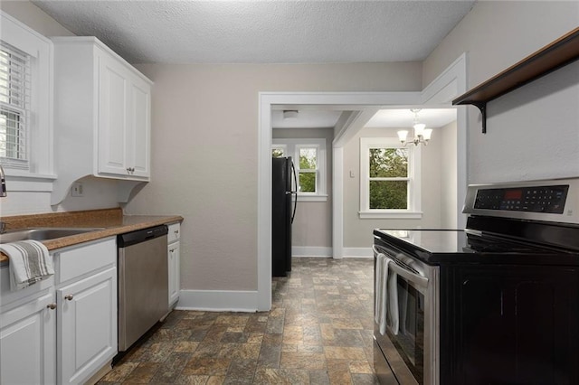 708 N River Blvd, Independence, MO 64050 - kitchen with appliances with stainless steel finishes, a sink, baseboards, white cabinets, and a notable chandelier