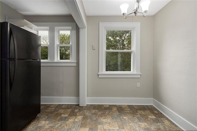 708 N River Blvd, Independence, MO 64050 - unfurnished dining area with an inviting chandelier, baseboards, and stone finish floor