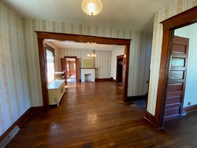 hall with dark wood-style flooring, wallpapered walls, and baseboards
