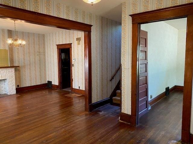interior space with an inviting chandelier, baseboards, dark wood-type flooring, and wallpapered walls