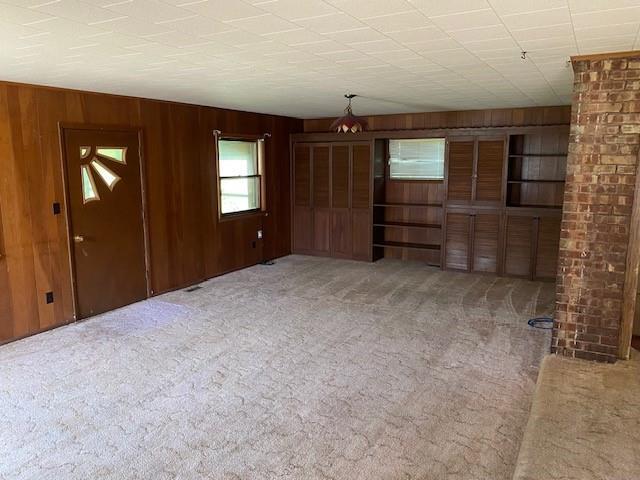unfurnished room with wood walls and carpet