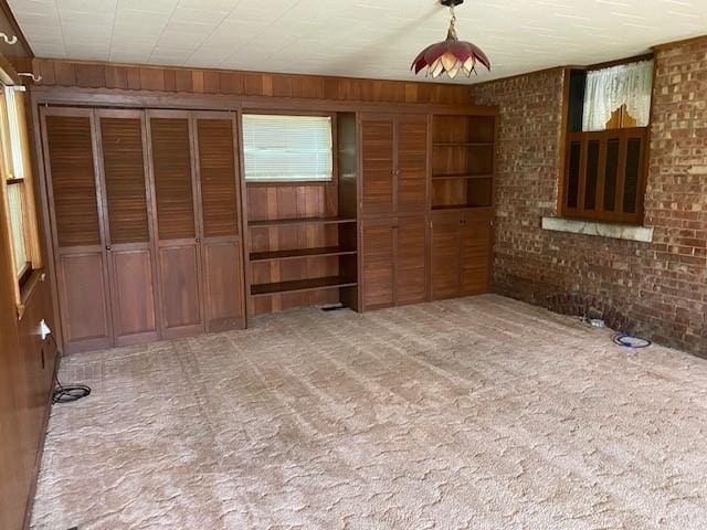 interior space with wooden walls, carpet floors, and brick wall