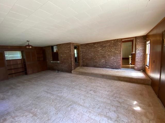 unfurnished living room with carpet and brick wall