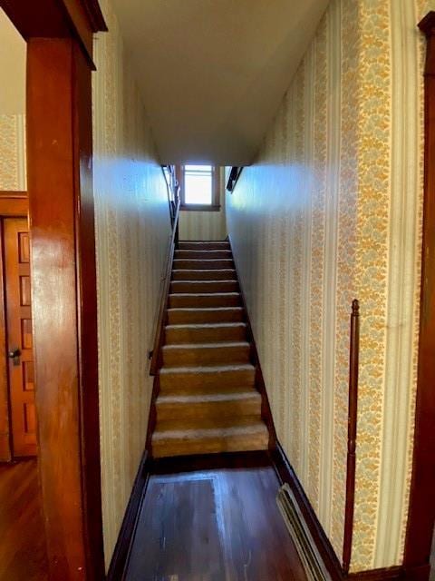stairs with wallpapered walls and wood finished floors