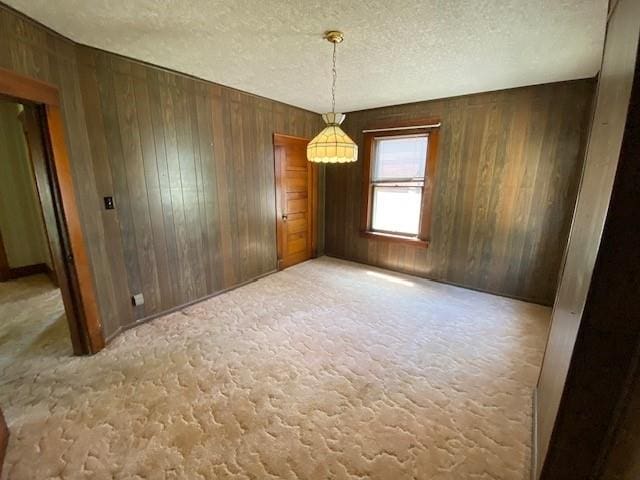 unfurnished dining area with wood walls, carpet, and a textured ceiling