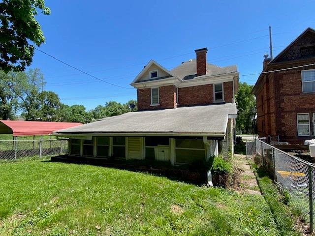 back of property with fence, a yard, and a chimney
