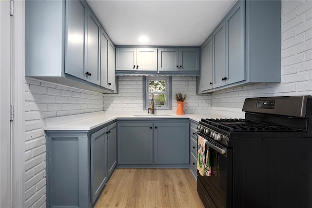4433 N Jackson Ave, Kansas City, MO 64117 - kitchen with light wood-style floors, light countertops, tasteful backsplash, a sink, and black gas range oven