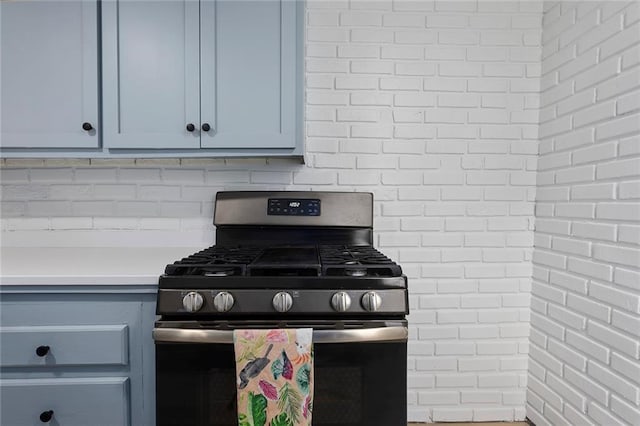 4433 N Jackson Ave, Kansas City, MO 64117 - kitchen with light countertops, decorative backsplash, blue cabinetry, and stainless steel gas stove