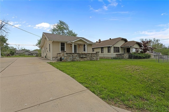 4433 N Jackson Ave, Kansas City, MO 64117 - view of front facade with driveway, fence, covered porch, and a front yard