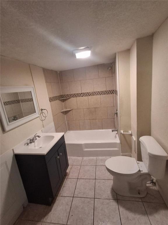 104 S 13th St, Kansas City, KS 66102 - bathroom with toilet, a textured ceiling, vanity, tile patterned flooring, and washtub / shower combination