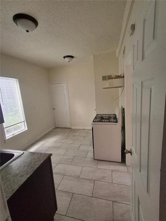 104 S 13th St, Kansas City, KS 66102 - kitchen with white range with gas cooktop, a textured ceiling, baseboards, and a sink