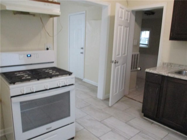 104 S 13th St, Kansas City, KS 66102 - kitchen with white range with gas stovetop, ventilation hood, and light countertops