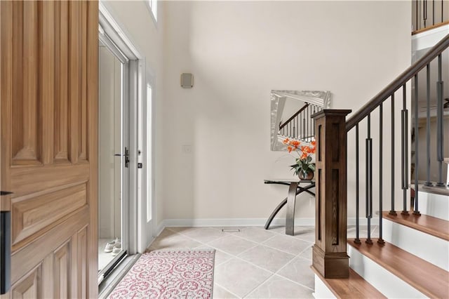 entrance foyer with baseboards, light tile patterned floors, stairway, and a towering ceiling