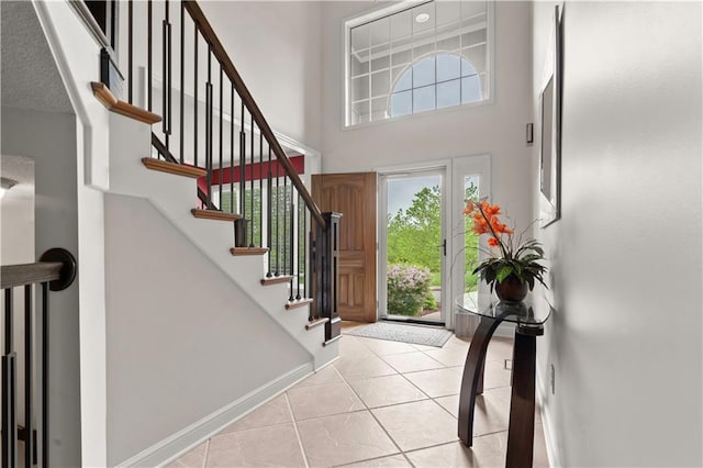 entryway with baseboards, a high ceiling, stairs, and light tile patterned flooring