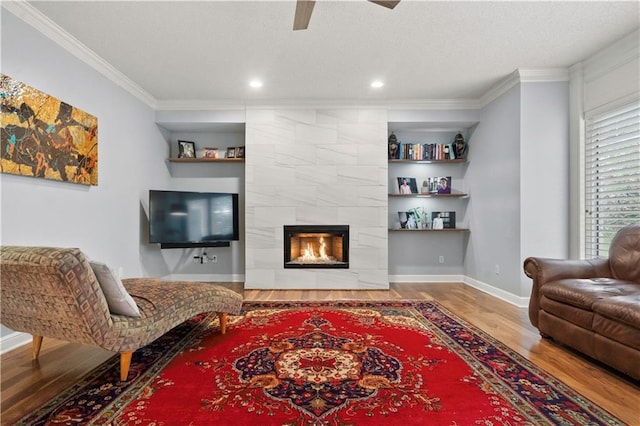 living area featuring baseboards, ceiling fan, ornamental molding, and wood finished floors