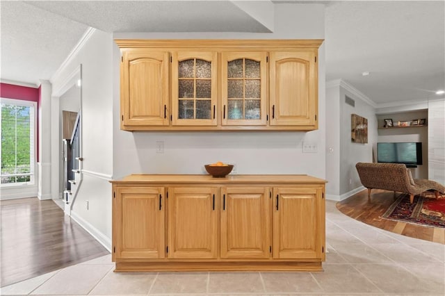 interior space with crown molding, visible vents, baseboards, a textured ceiling, and light tile patterned floors