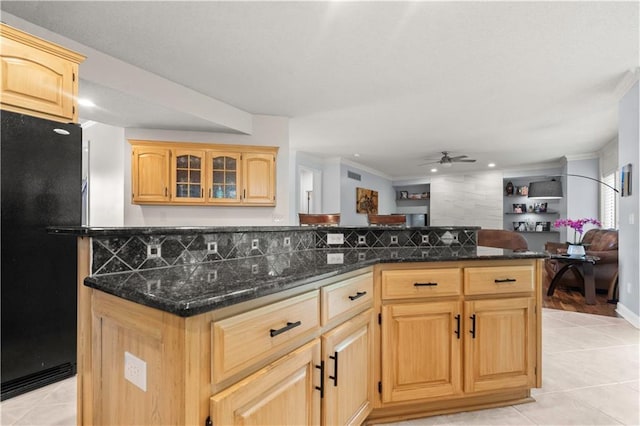 kitchen with freestanding refrigerator, dark stone countertops, a ceiling fan, and light tile patterned flooring