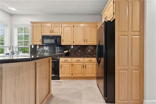 kitchen featuring backsplash, dark stone counters, a sink, black appliances, and light brown cabinets