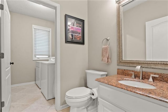 bathroom with vanity, toilet, tile patterned floors, baseboards, and washing machine and dryer