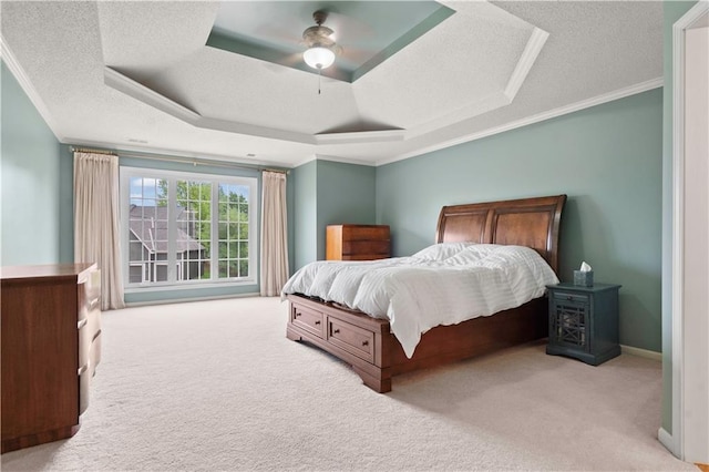 bedroom with crown molding, carpet floors, a textured ceiling, a ceiling fan, and a tray ceiling