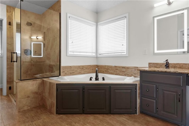 full bathroom with vanity, a bath, and a tile shower