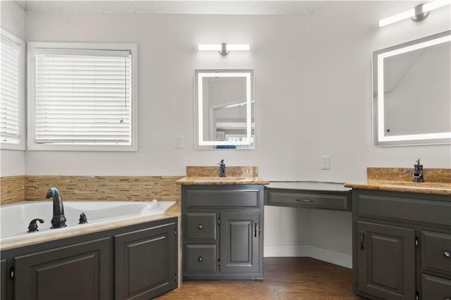 bathroom with a bath, vanity, baseboards, and wood finished floors