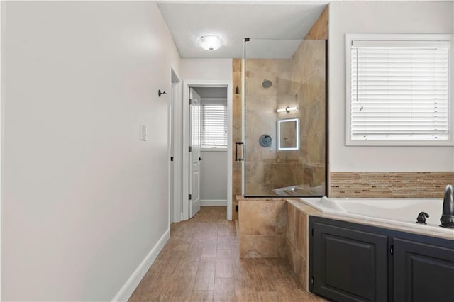 bathroom with a sink, baseboards, wood finished floors, tiled shower, and a garden tub