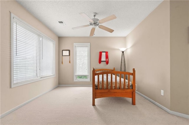 carpeted bedroom featuring baseboards, a ceiling fan, a textured ceiling, and visible vents