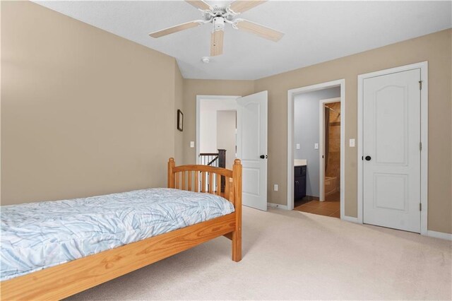 bedroom featuring connected bathroom, baseboards, light carpet, and ceiling fan