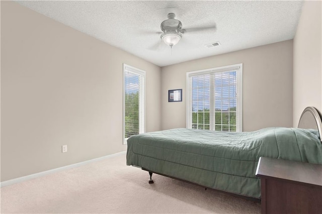 carpeted bedroom featuring baseboards, a ceiling fan, and visible vents