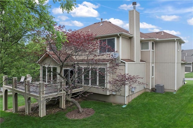 rear view of house featuring a chimney, roof with shingles, a deck, central AC unit, and a yard